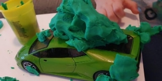 Green toy car is covered with green play doh