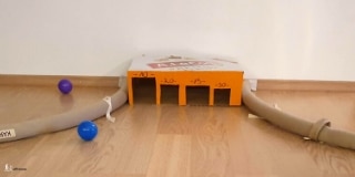 DIY mini golf box with holes and two plastic balls on the floor