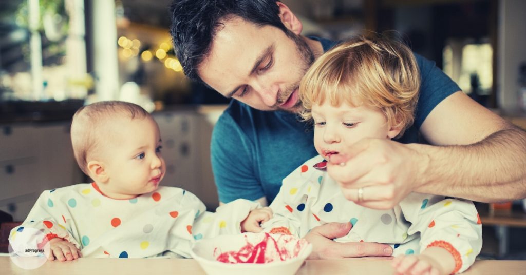 Father feeding a toddler and a baby