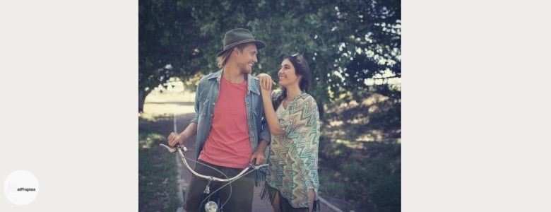 man on a bike looking at a woman who's standing next to him, both are smiling