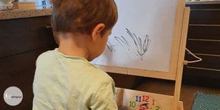 toddler before a whiteboard and some marking on the board