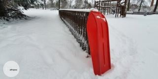 red sledge against a fence and a lot of snow